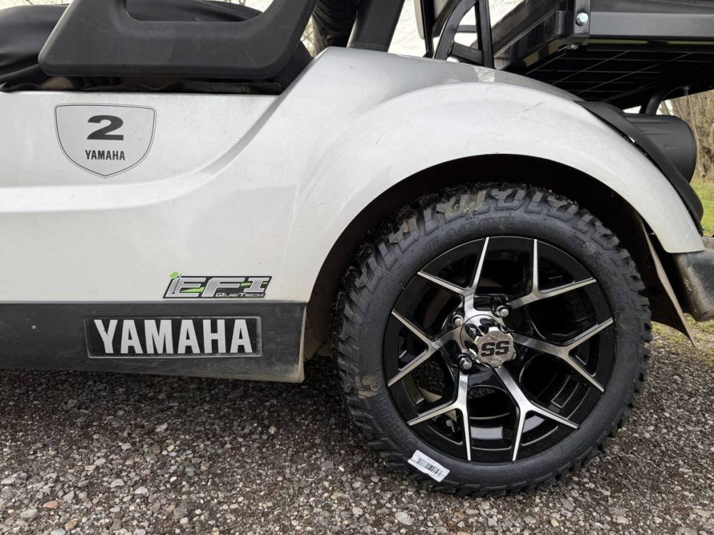 Black and machined golf cart wheel with all-terrain tire on a silver Yamaha