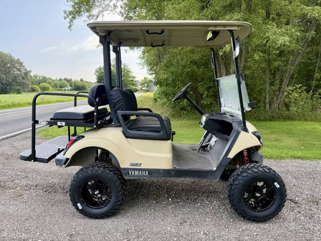 Lifted tan golf cart side view with all-terrain wheels and tires